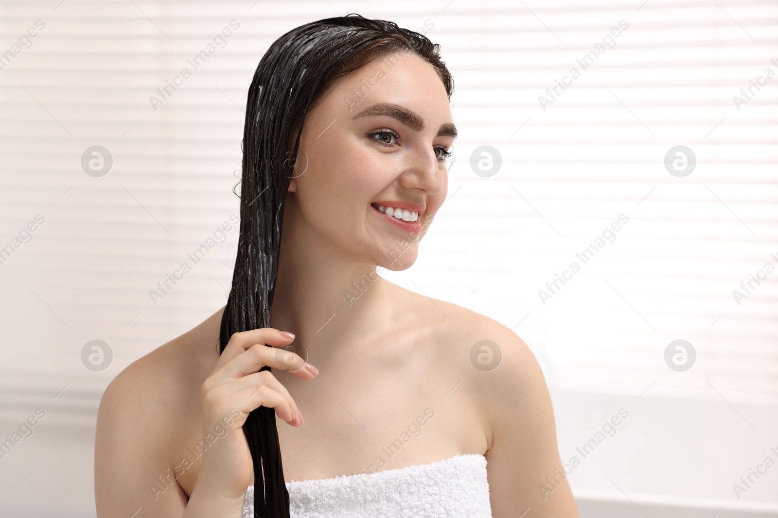 Photo of Smiling woman with applied hair mask in bathroom
