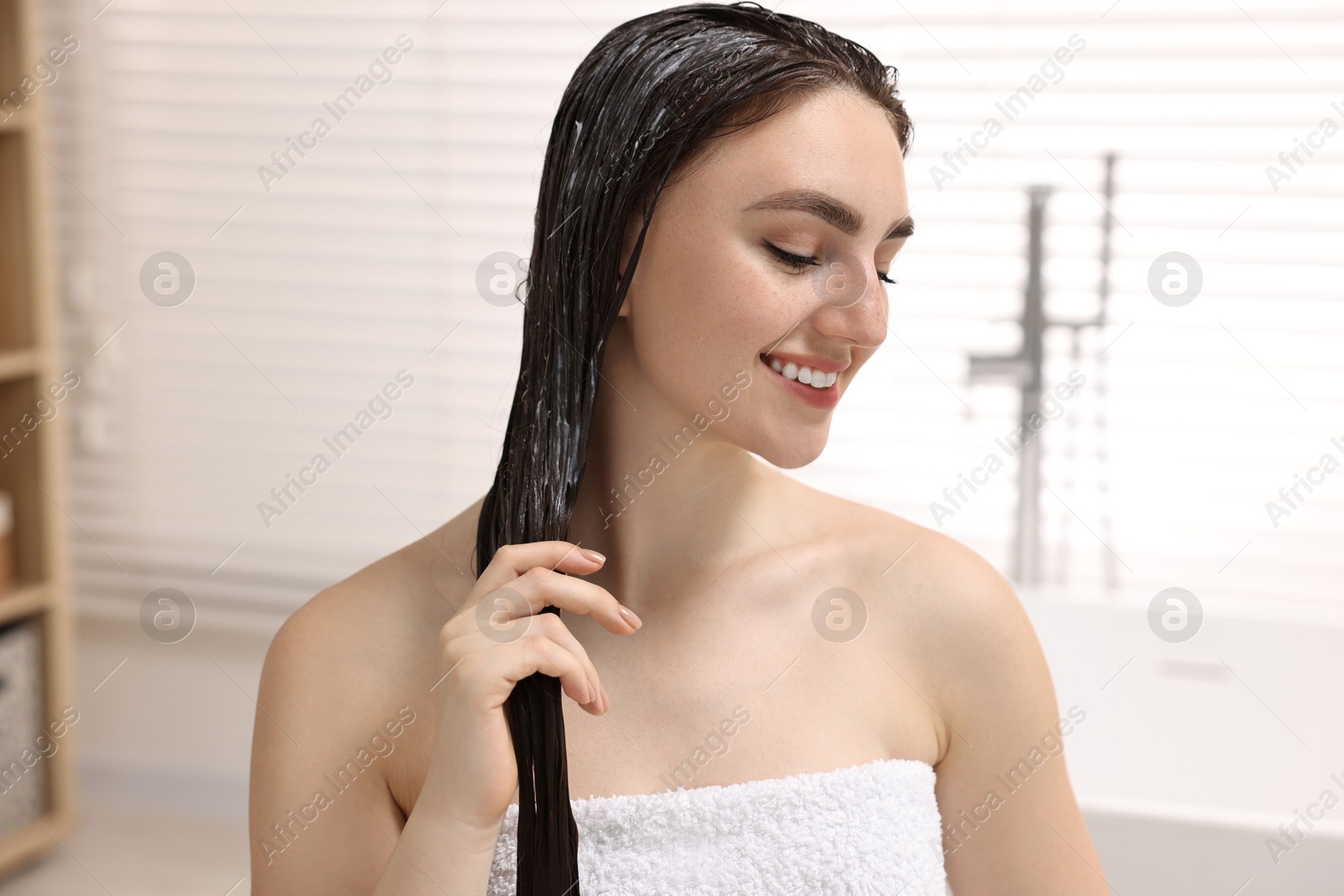 Photo of Smiling woman with applied hair mask in bathroom