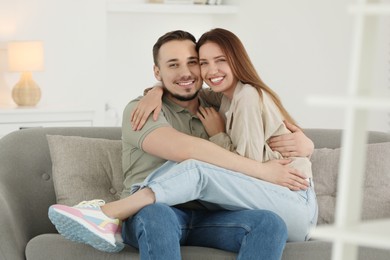 Photo of Happy man hugging his girlfriend on sofa at home