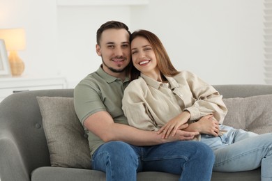 Photo of Happy man hugging his girlfriend on sofa at home