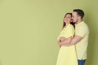 Man hugging his happy girlfriend on green background. Space for text