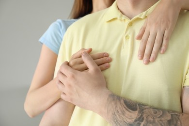Photo of Woman hugging her boyfriend on light background, closeup