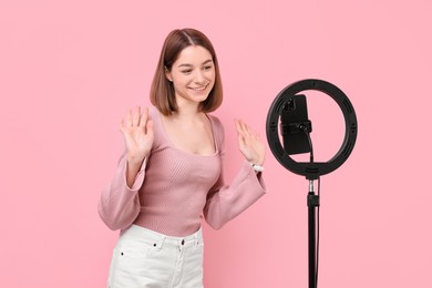 Blogger recording video with smartphone and ring lamp on pink background