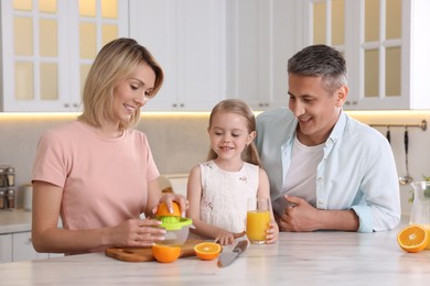 Happy family with juicer and fresh products making juice at white marble table in kitchen
