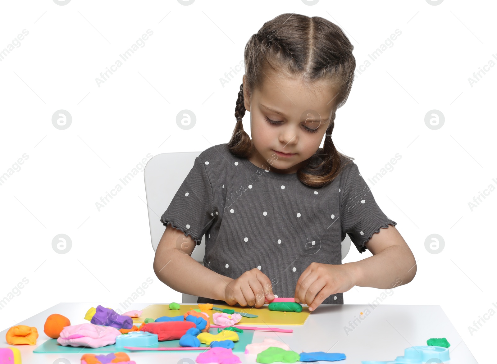 Photo of Little girl sculpting with play dough at table on white background