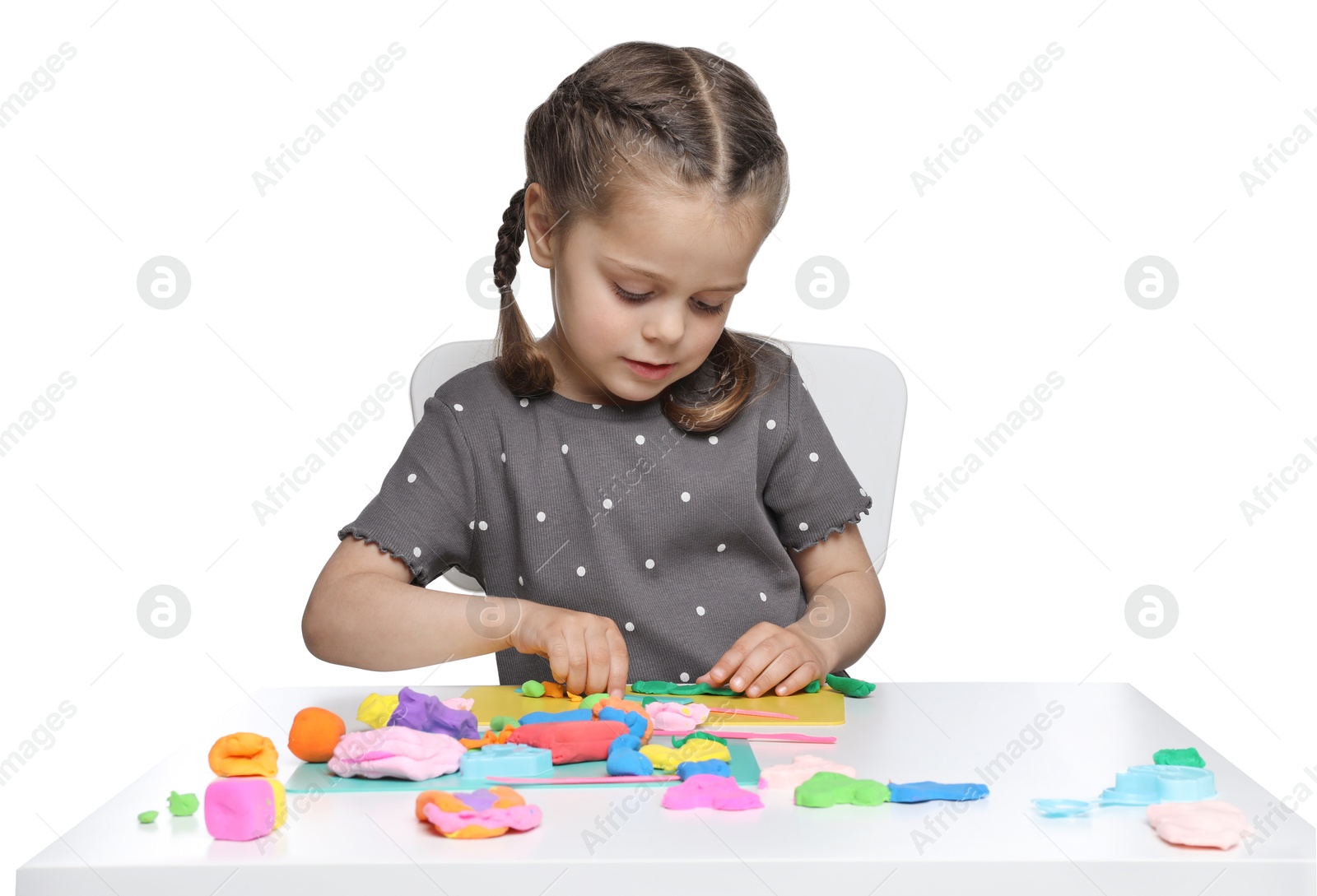 Photo of Little girl sculpting with play dough at table on white background