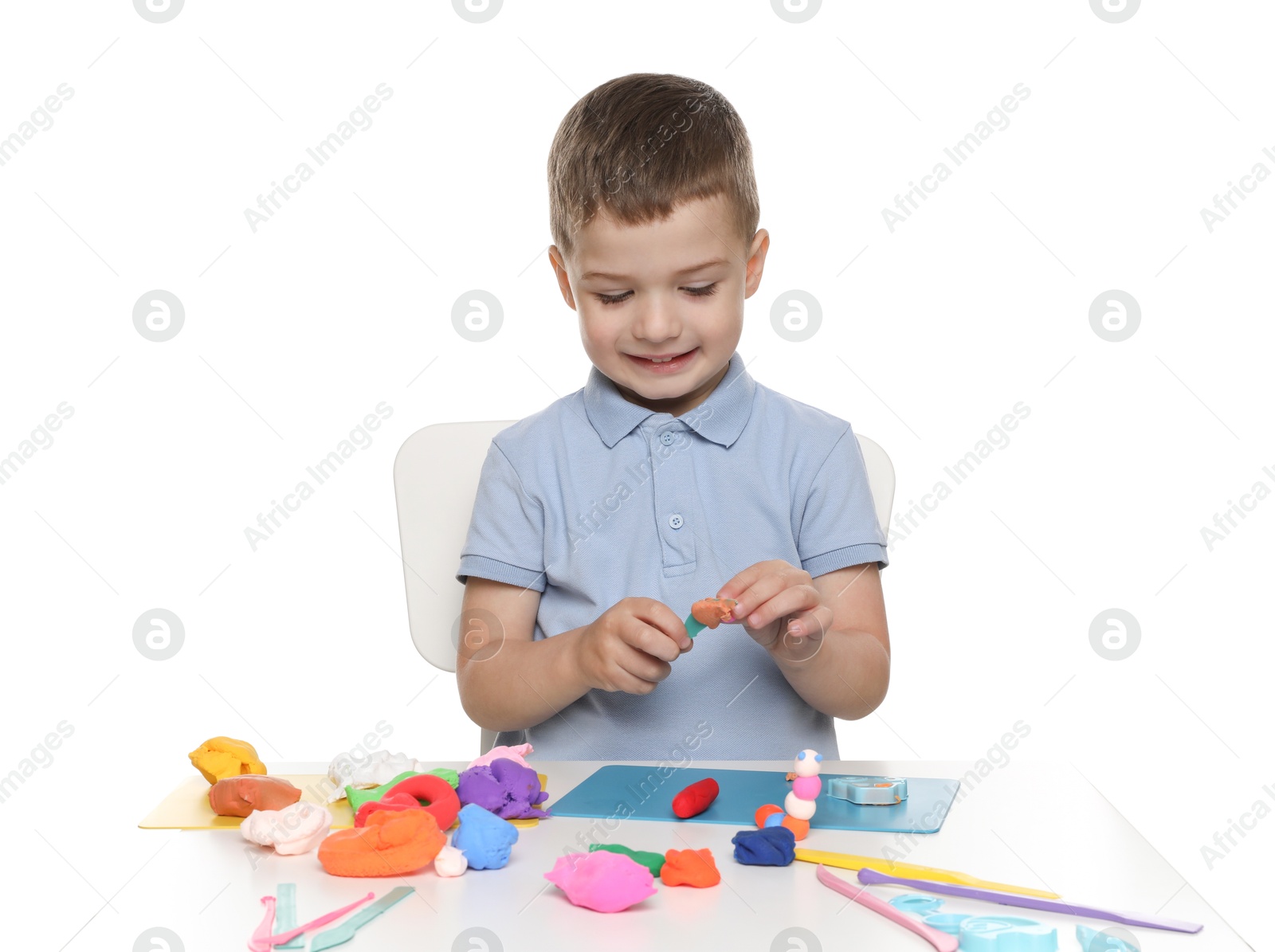 Photo of Smiling boy with play dough handiwork at table on white background