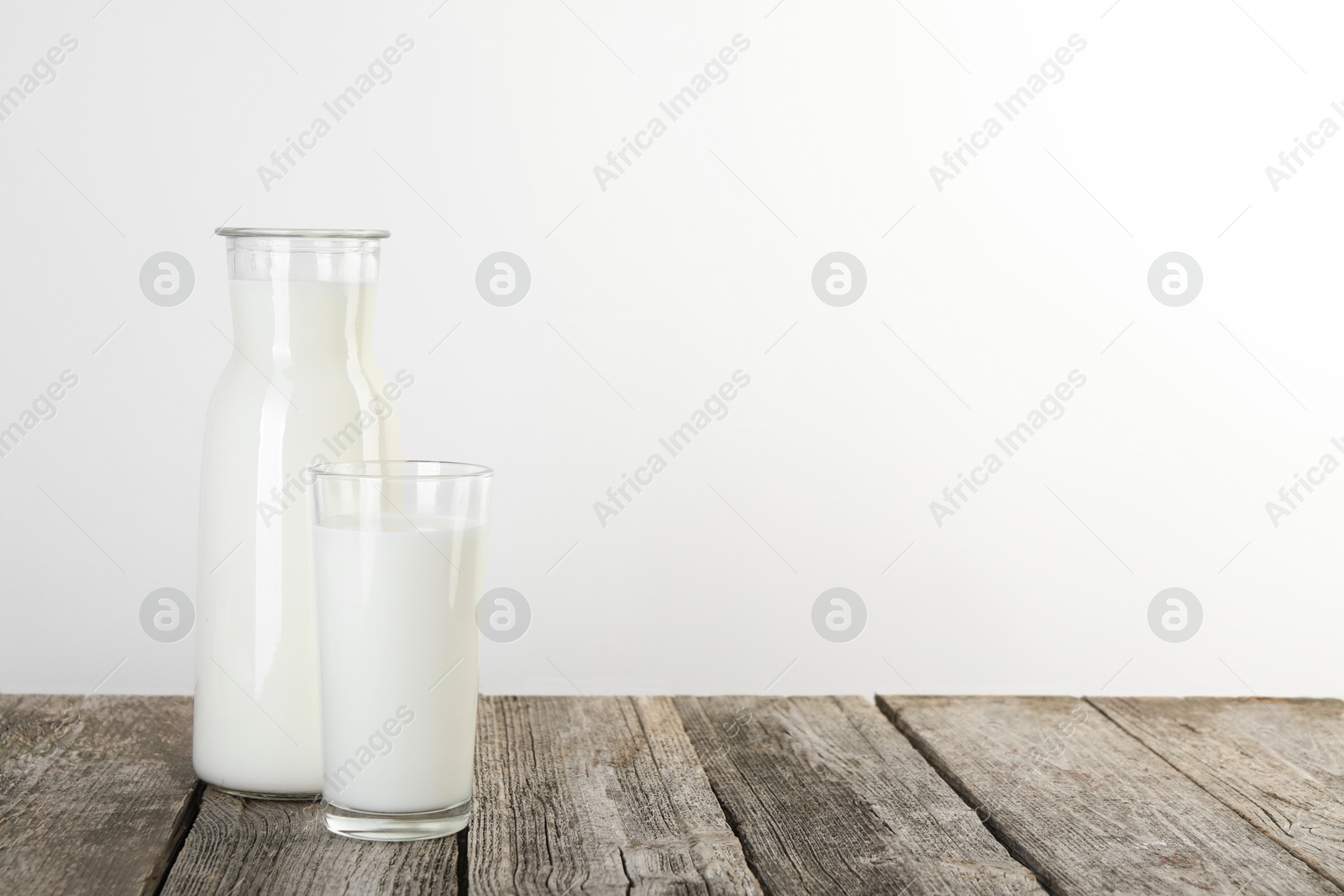 Photo of Carafe and glass of fresh milk on wooden table, space for text