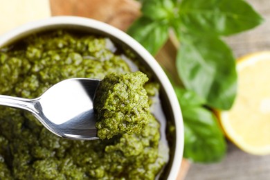 Photo of Taking tasty pesto sauce at table, top view