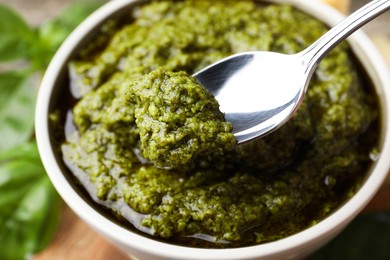 Photo of Taking tasty pesto sauce at table, closeup