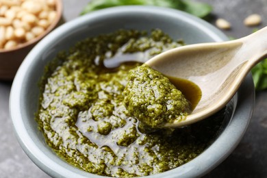 Photo of Taking tasty pesto sauce at table, closeup