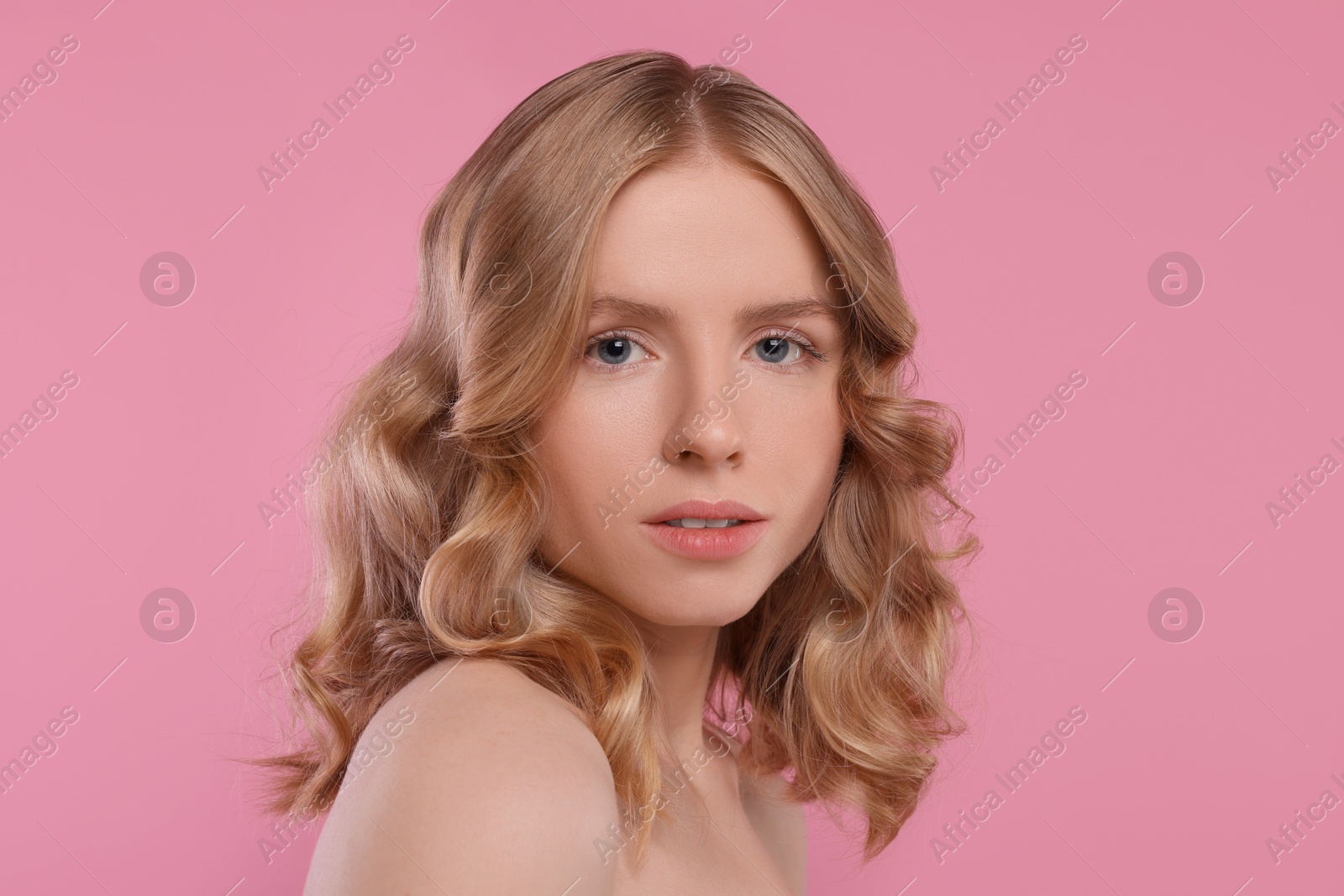 Photo of Portrait of beautiful woman with blonde hair on pink background