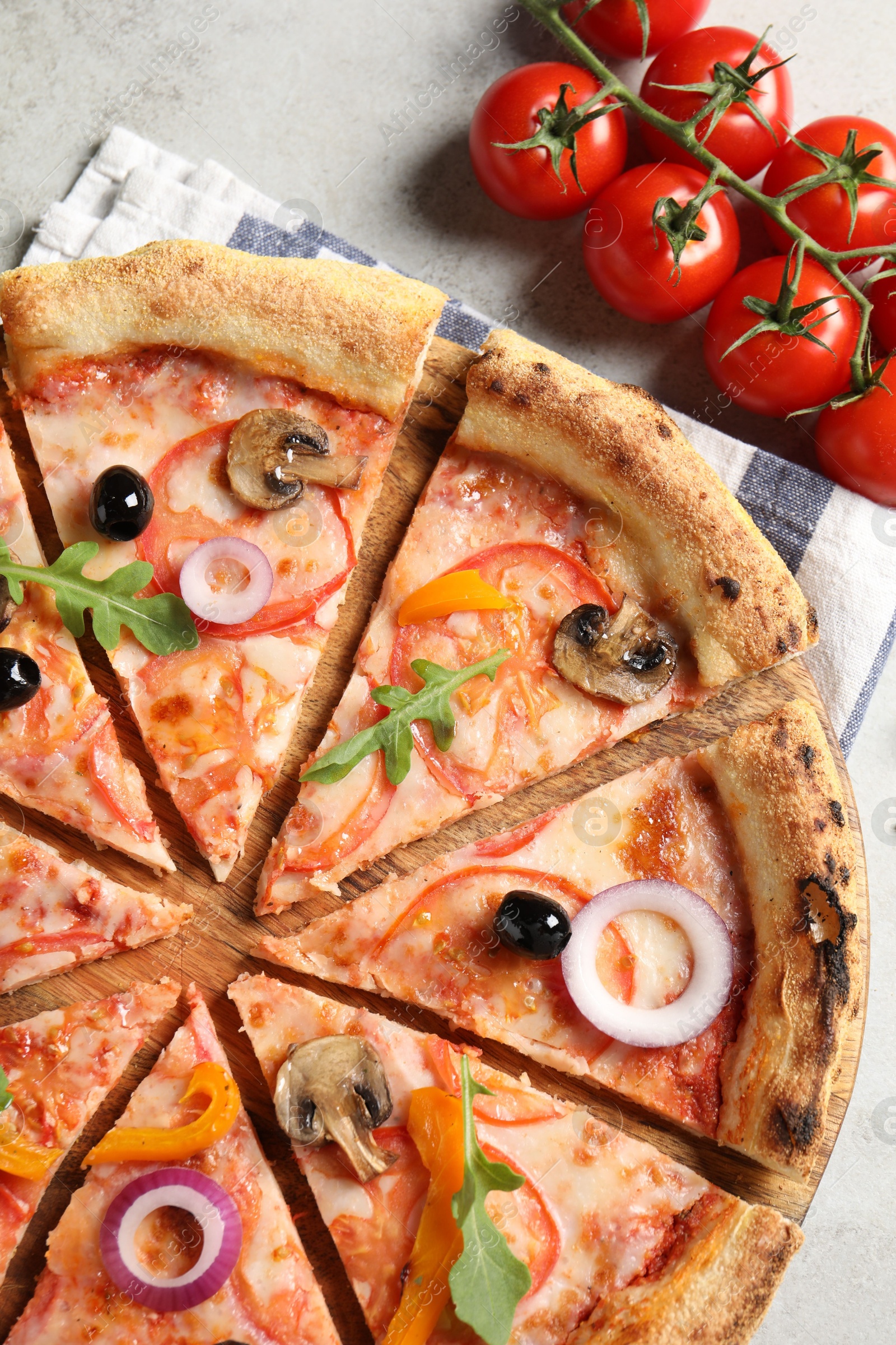 Photo of Cut delicious vegetarian pizza and tomatoes on light table, top view