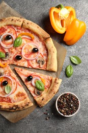 Photo of Cut delicious vegetarian pizza and ingredients on grey table, flat lay