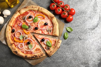 Photo of Cut delicious vegetarian pizza and ingredients on grey table, flat lay. Space for text