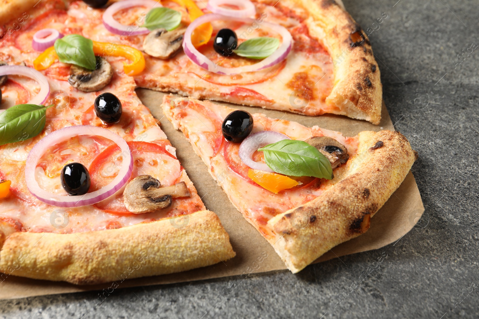 Photo of Cut delicious vegetarian pizza on grey table, closeup