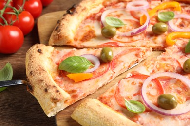 Photo of Cut delicious vegetarian pizza on wooden table, closeup