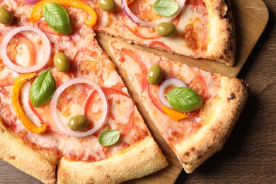 Photo of Cut delicious vegetarian pizza on wooden table, top view