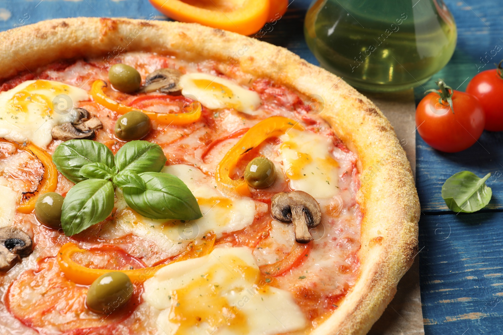 Photo of Delicious vegetarian pizza and ingredients on blue wooden table, closeup