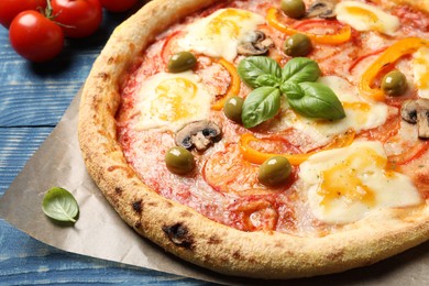 Photo of Delicious vegetarian pizza and ingredients on blue wooden table, closeup