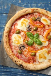 Photo of Delicious vegetarian pizza on blue wooden table, top view