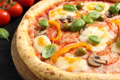 Photo of Delicious vegetarian pizza on black wooden table, closeup