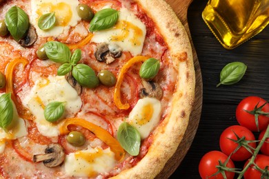 Photo of Delicious vegetarian pizza on black wooden table, closeup