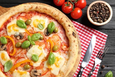 Photo of Delicious vegetarian pizza served on black wooden table, top view