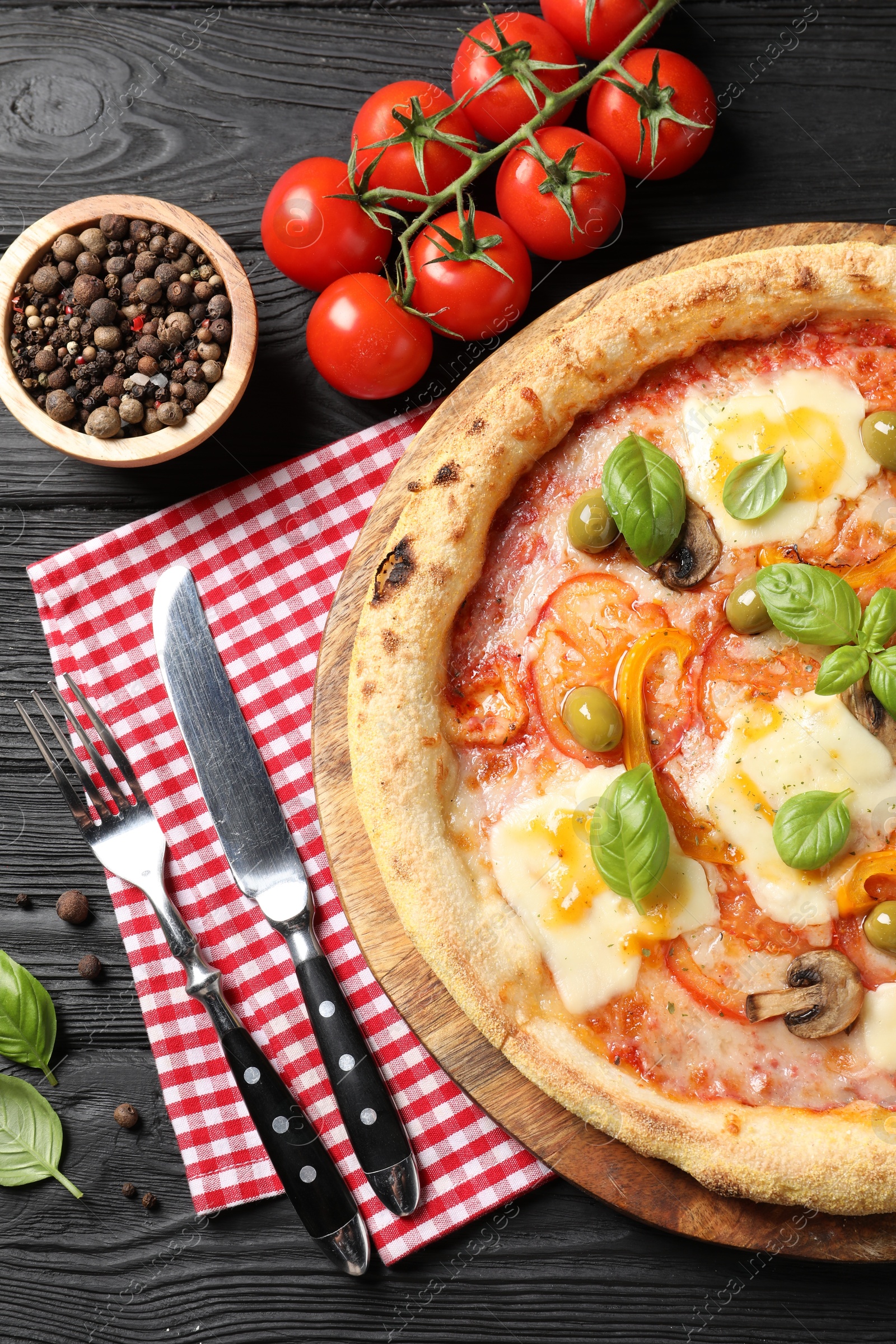 Photo of Delicious vegetarian pizza served on black wooden table, top view