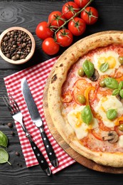 Photo of Delicious vegetarian pizza served on black wooden table, top view