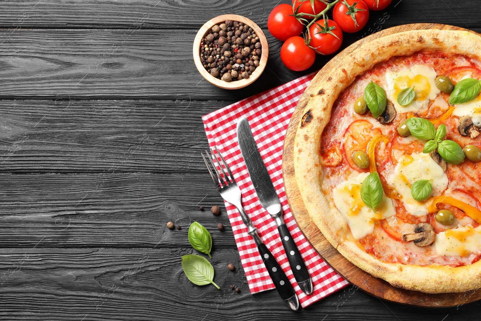 Photo of Delicious vegetarian pizza served on black wooden table, top view. Space for text