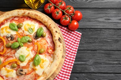 Photo of Delicious vegetarian pizza served on black wooden table, top view. Space for text