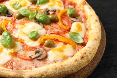 Photo of Delicious vegetarian pizza on black wooden table, closeup