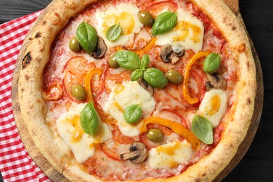 Photo of Delicious vegetarian pizza on black wooden table, top view