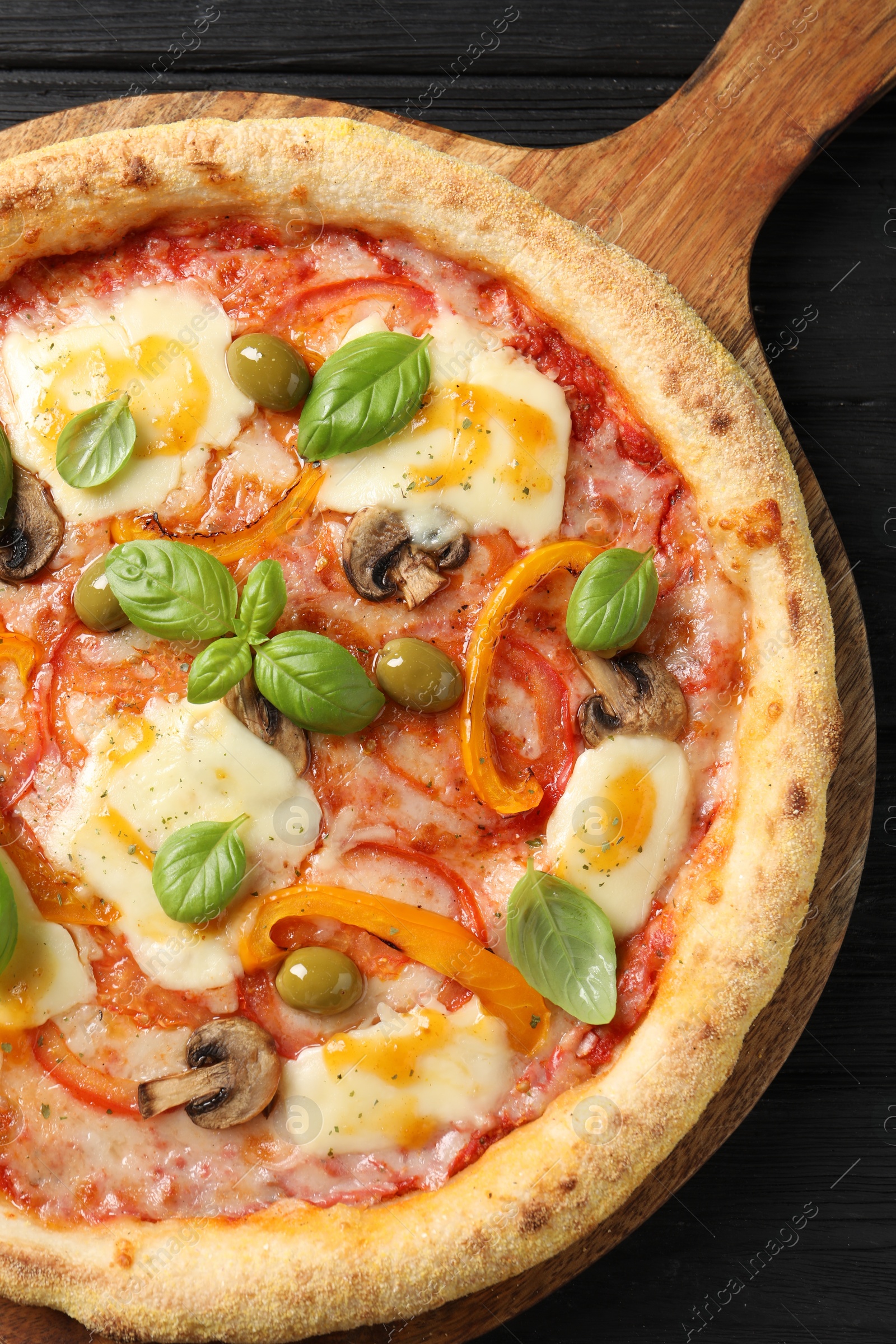 Photo of Delicious vegetarian pizza on black wooden table, top view