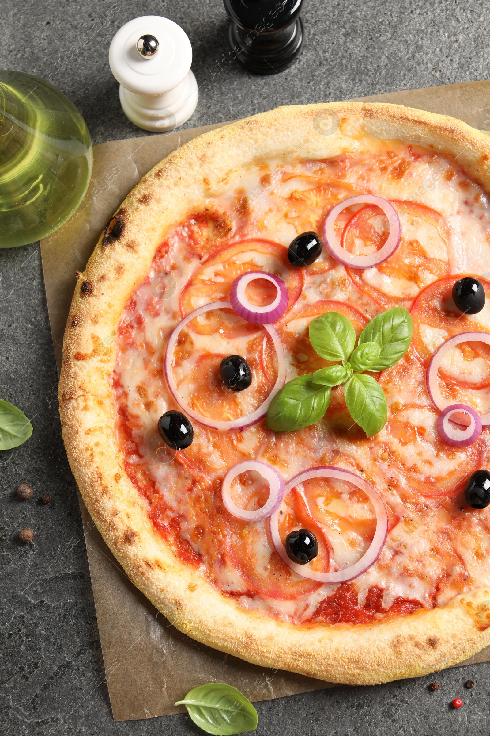 Photo of Delicious vegetarian pizza, oil, salt and pepper on grey table, top view