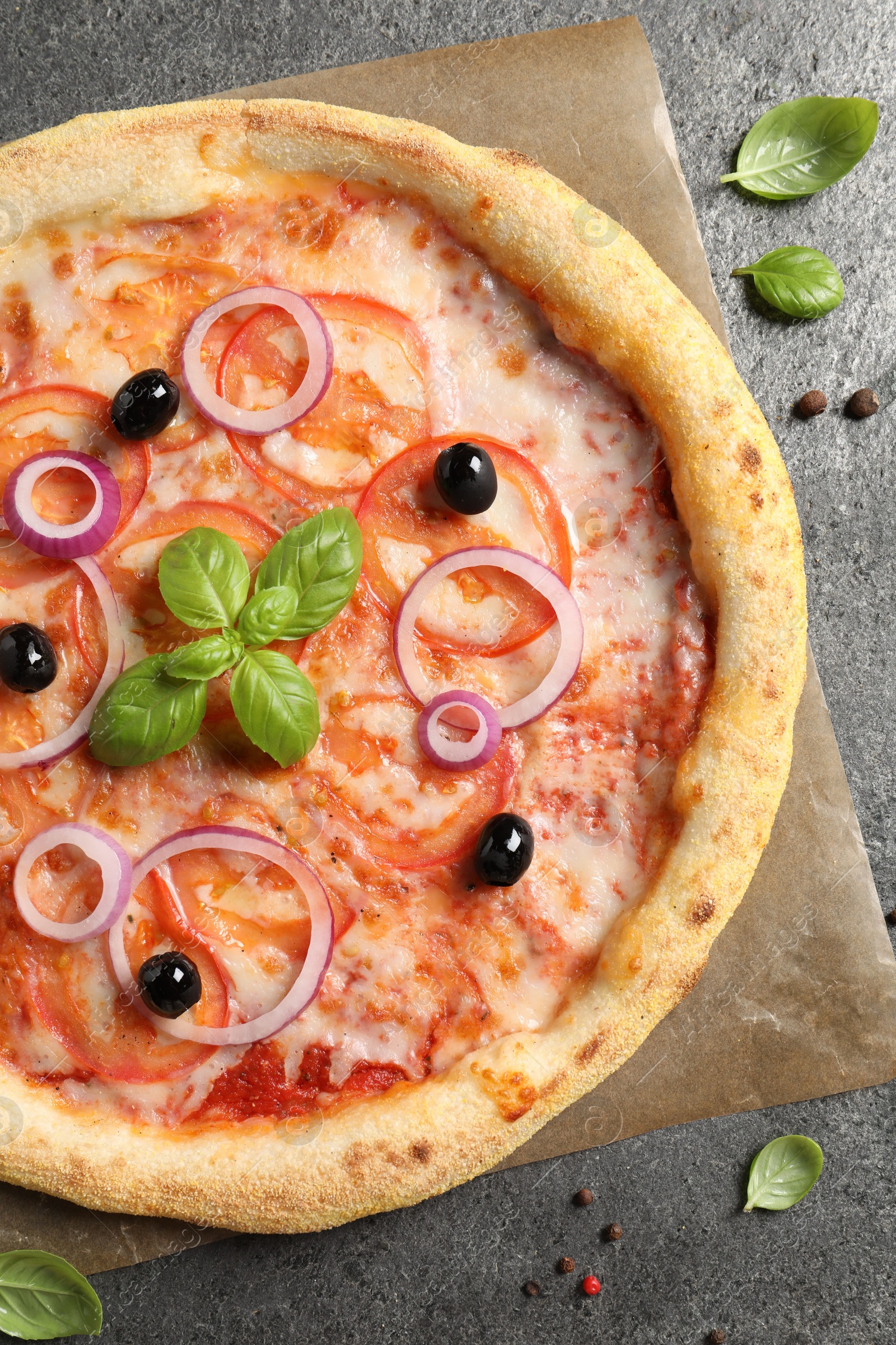 Photo of Delicious vegetarian pizza with basil and peppercorns on grey table, top view