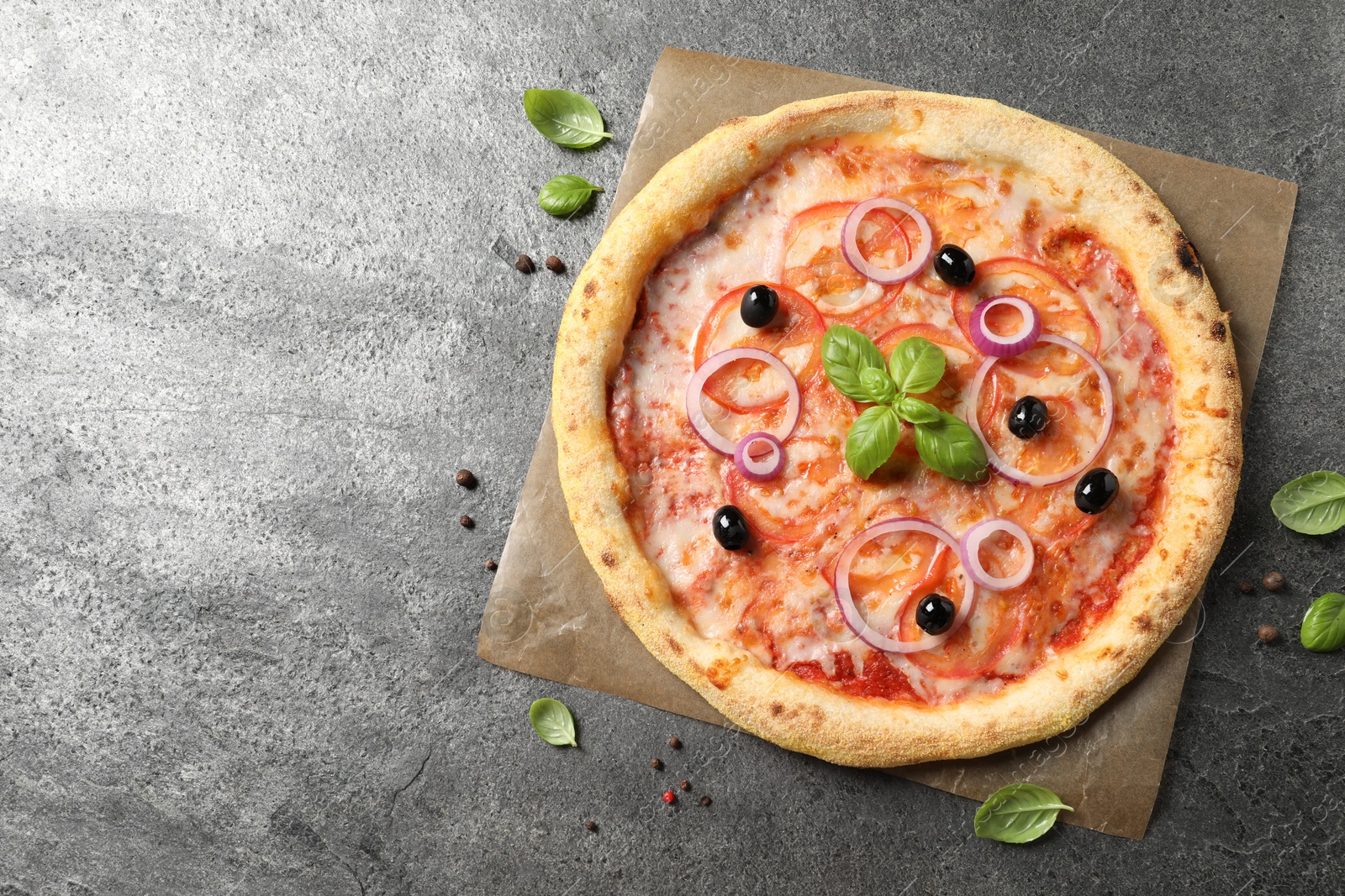 Photo of Delicious vegetarian pizza with basil and peppercorns on grey table, top view