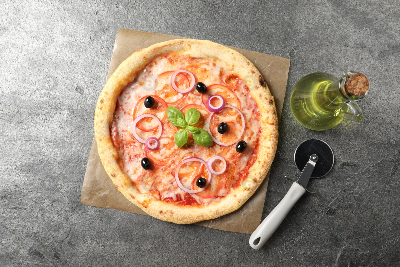 Photo of Delicious vegetarian pizza, cutter and oil on grey table, top view