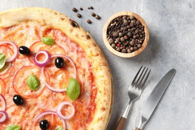 Photo of Delicious vegetarian pizza, peppercorns and cutlery on light grey table, top view