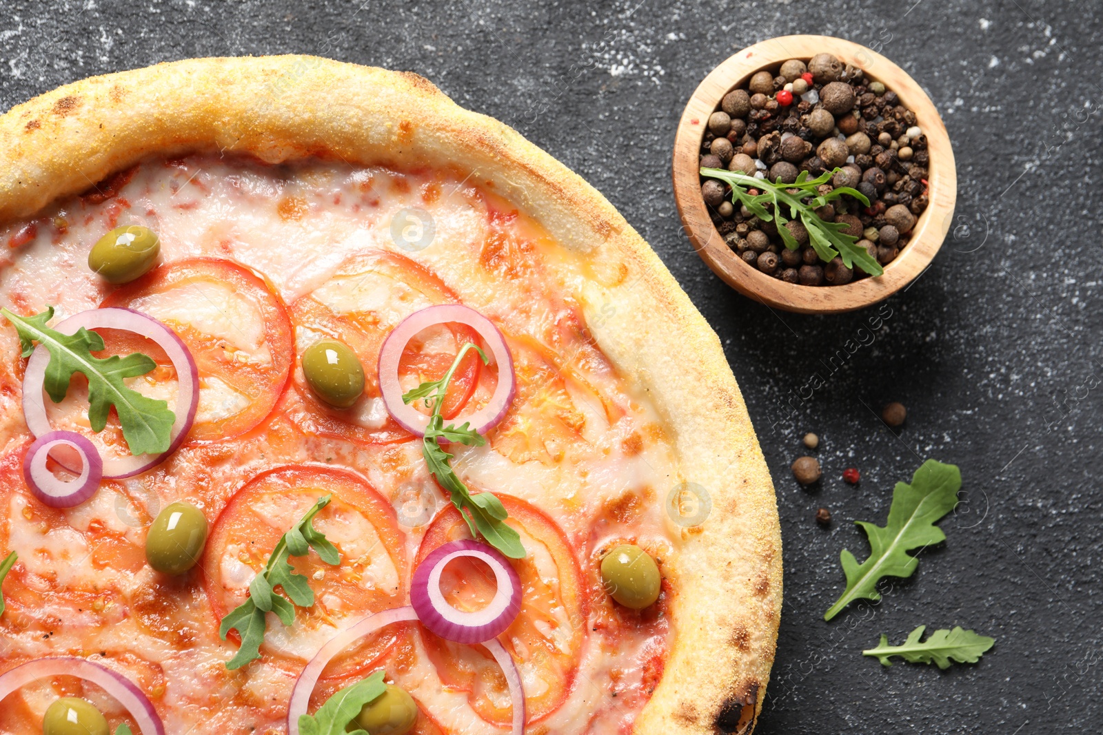 Photo of Delicious vegetarian pizza with arugula and peppercorns on black table, top view