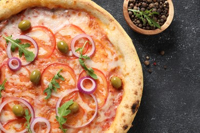 Photo of Delicious vegetarian pizza with arugula and peppercorns on black table, top view