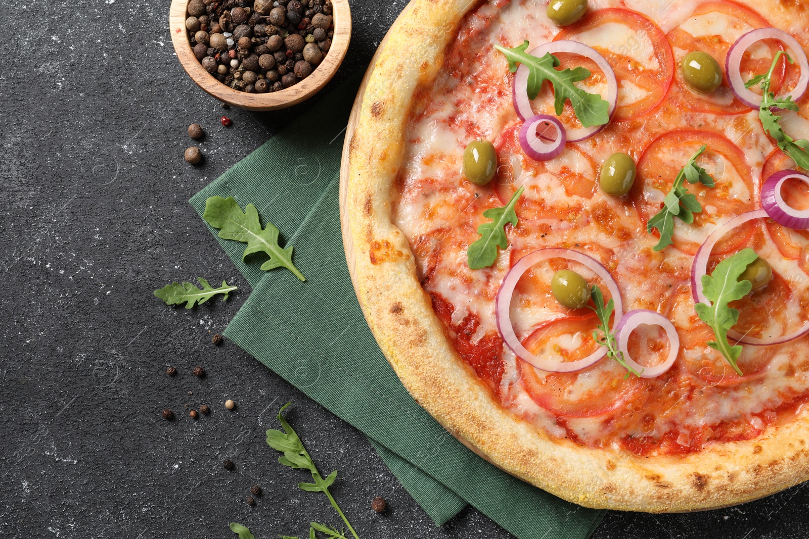 Photo of Delicious vegetarian pizza with arugula and peppercorns on black table, top view