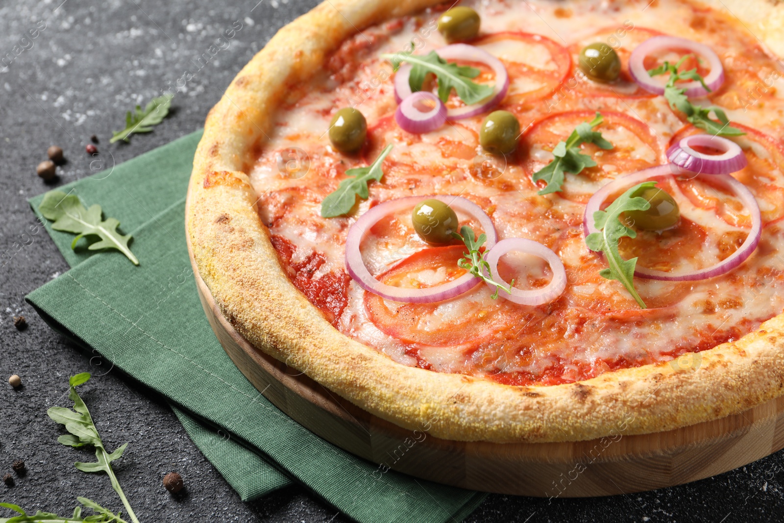 Photo of Delicious vegetarian pizza, arugula and peppercorns on black table, closeup