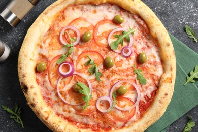 Photo of Delicious vegetarian pizza, arugula, salt and pepper on black table, top view