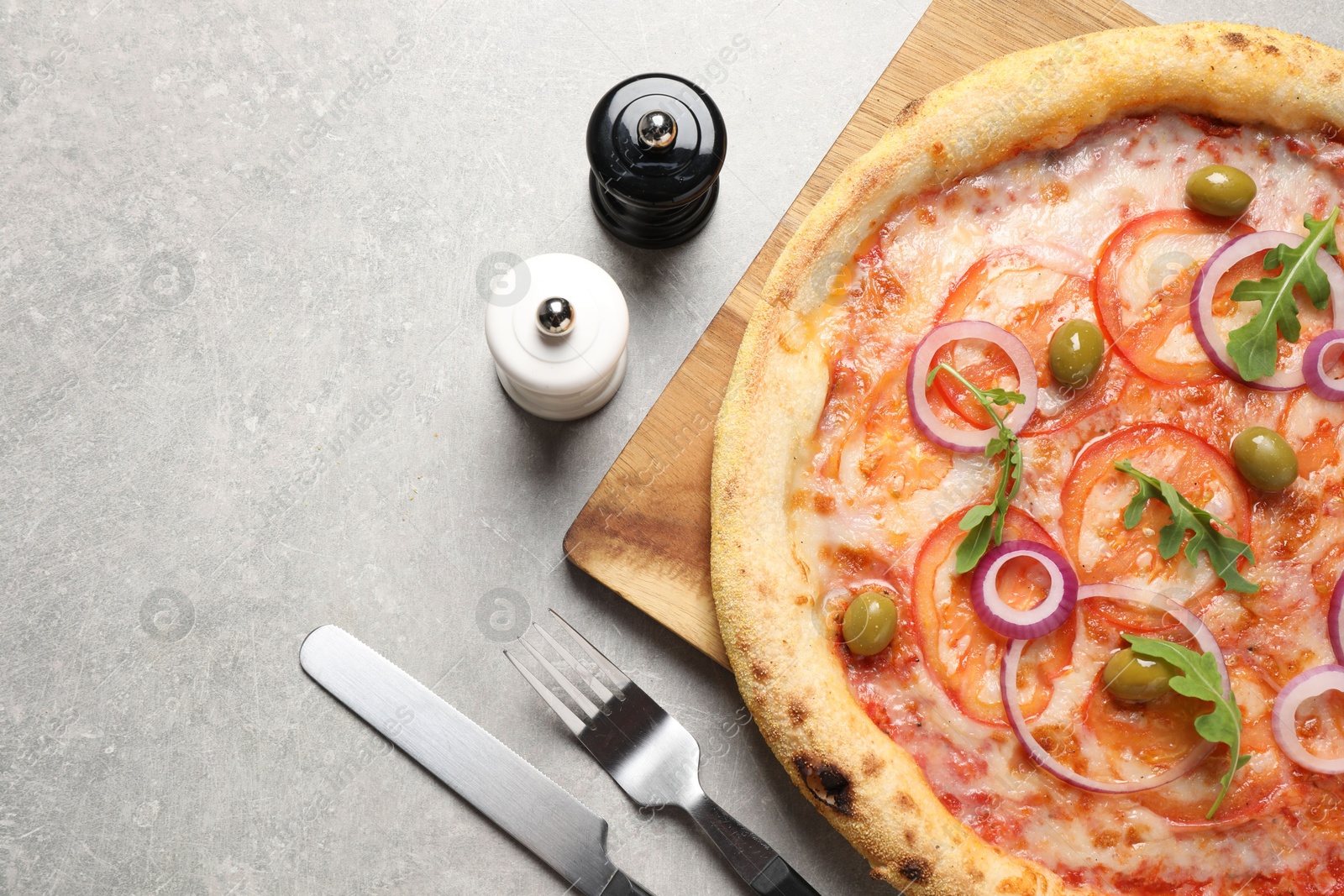 Photo of Delicious vegetarian pizza, cutlery, salt and pepper on light grey background, top view. Space for text