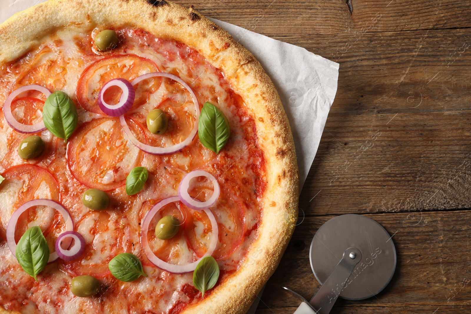 Photo of Delicious vegetarian pizza and cutter on wooden table, top view