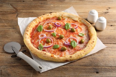 Photo of Delicious vegetarian pizza and cutter on wooden table