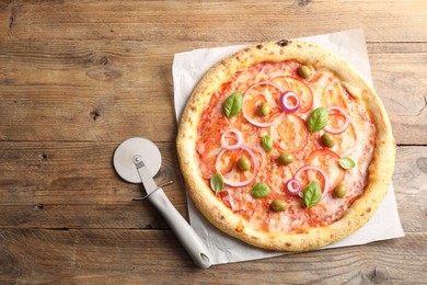 Photo of Delicious vegetarian pizza and cutter on wooden table, top view