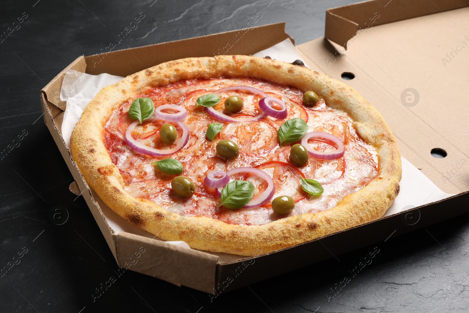 Photo of Delicious vegetarian pizza in box on black table, closeup